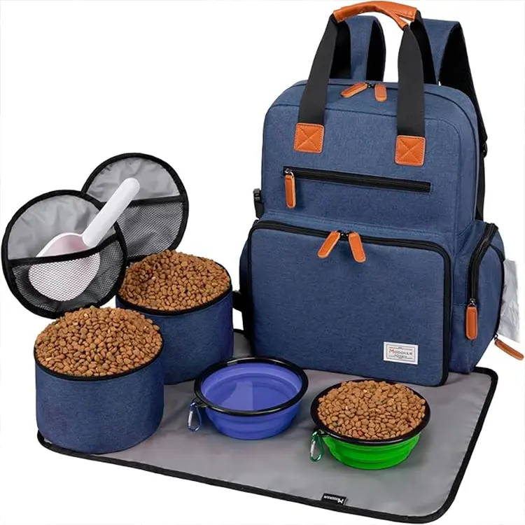 A Backpack for Dog Accessories in blue with tan accents is shown open, displaying two container lids with scoops, two full food containers, and two collapsible bowls—one blue and one green—on a gray mat.