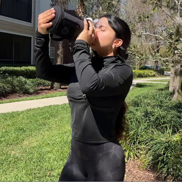 Person drinking from the 37oz Insulated Stainless Steel Dog & Human Water Bottle with detachable bowl, designed for walking, hiking, camping, and outdoor travel